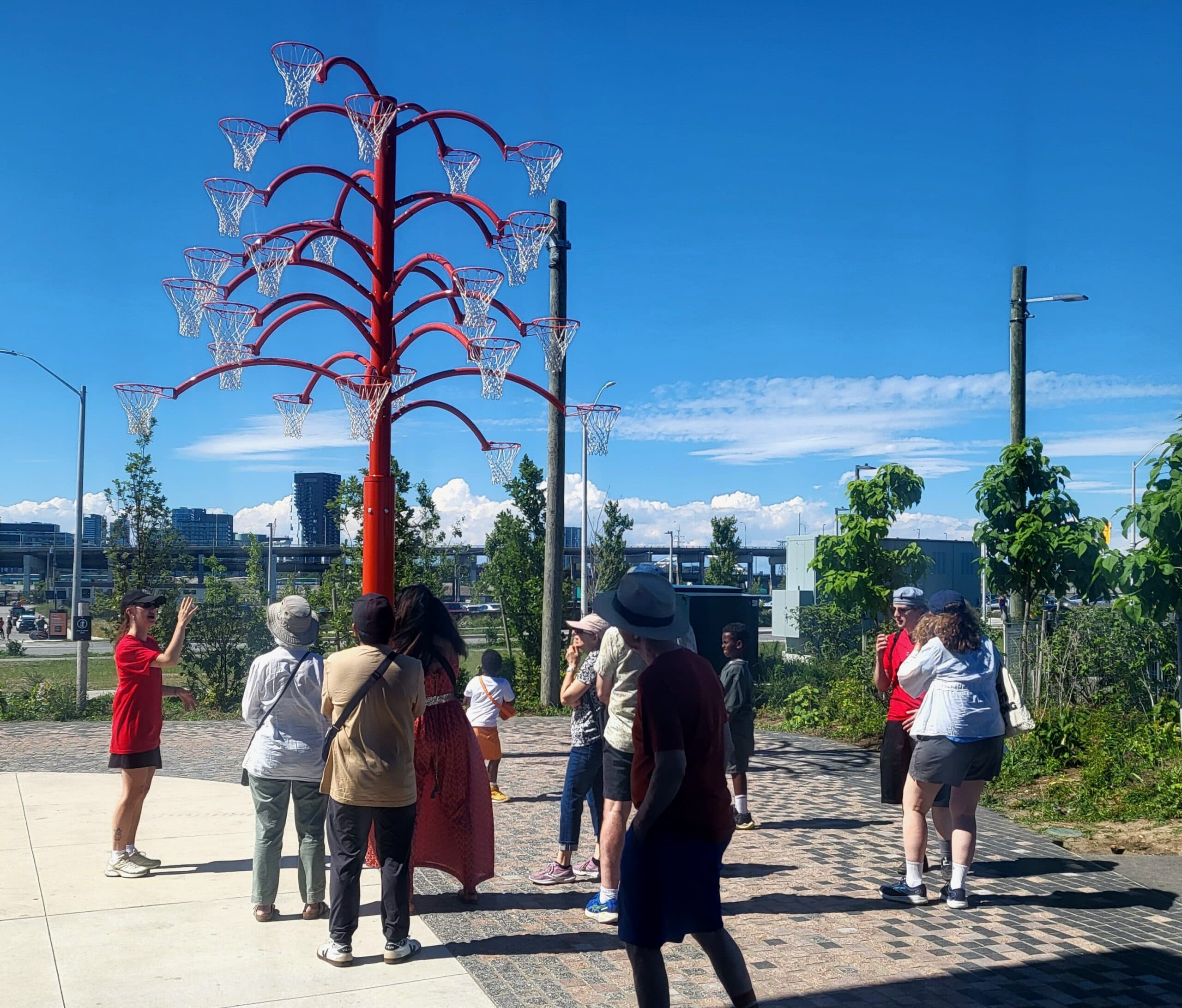 A group of people gathered around a tree-like structure of basketball nets